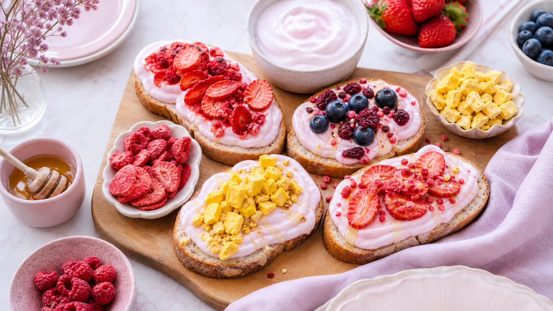 Brunch board with pink yogurt toast slices topped with freeze-dried strawberries, mango, berries, and honey on a soft pink table setting