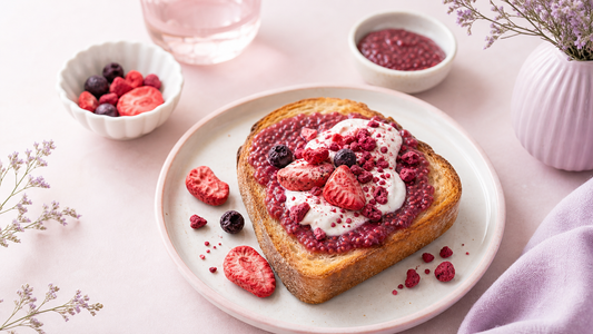 An airy brunch scene with thick toast topped with rosy chia jam, dollops of yogurt, crushed freeze-dried berries, and pale pink table styling for How to Make Chia Jam Toast With Freeze-Dried Fruit.