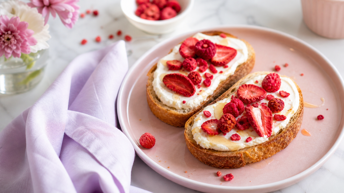 Two slices of mascarpone toast topped with freeze-dried strawberries and raspberries on a pale pink brunch plate