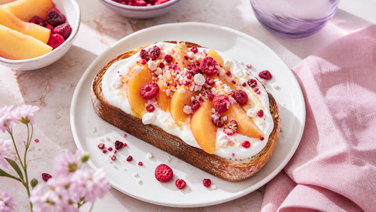 Peach yogurt toast topped with freeze-dried fruit on a white breakfast plate with blush napkin and airy lavender styling