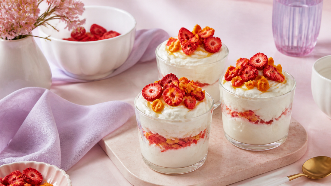 Three whipped labneh snack cups topped with freeze-dried strawberries and mango on a pale blush brunch table with white ceramics and soft lavender styling