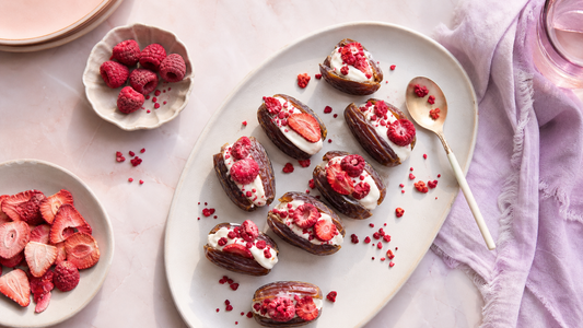 Platter of yogurt-stuffed dates topped with freeze-dried strawberries and raspberries on a pale pink brunch table