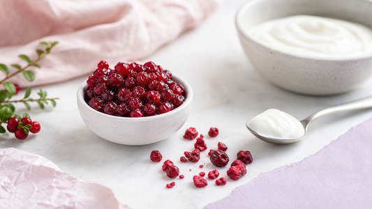 Editorial breakfast scene with small bowls of lingonberries, freeze-dried berry pieces, white yogurt, and blush lavender linens in soft natural light